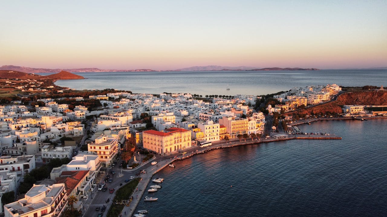 Stunning aerial view of Tinos Island coastline, capturing the vibrant sunset hues and tranquil sea.